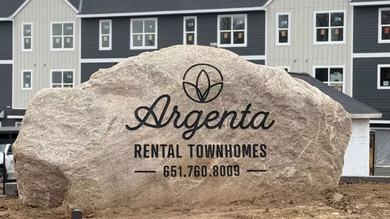 Large Rock with Argenta Townhomes logo with newly built townhomes in the background 
