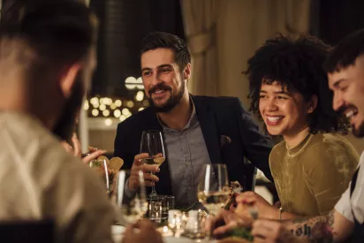 Friends gathered around a table with wine and dinner laughing with one another